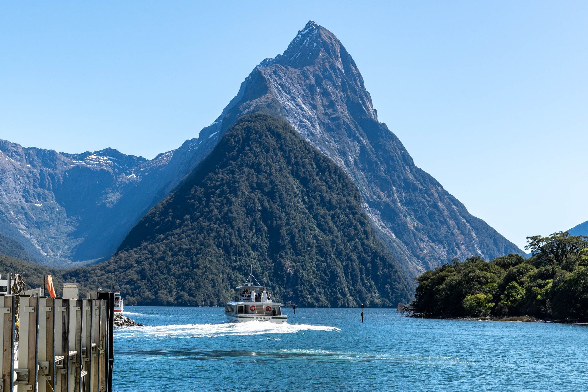 Milford Sound cruise vessel near towering waterfall